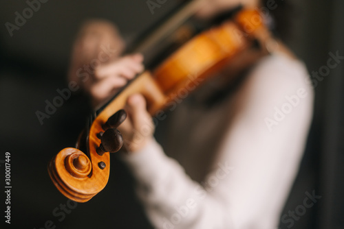 Beautiful woman musician plays the violin in her home, close-up. Female 's face is not visible.