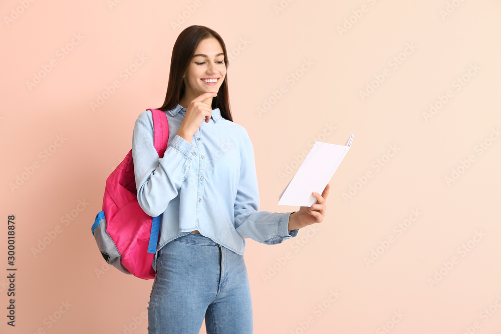 Fototapeta premium Portrait of teenage schoolgirl with book on color background