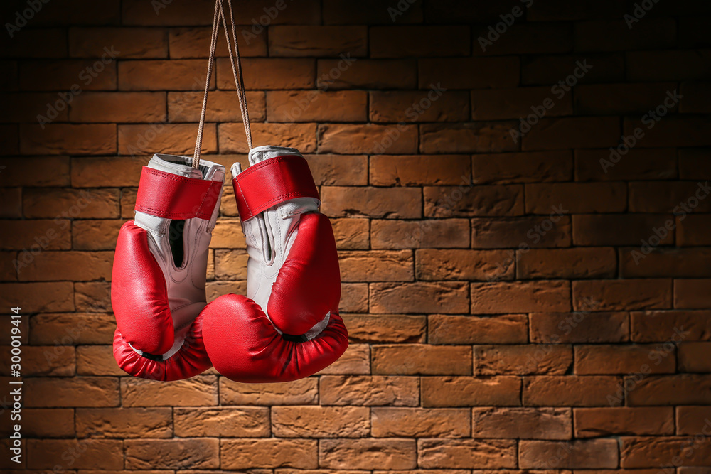 Pair of boxing gloves hanging against brick wall