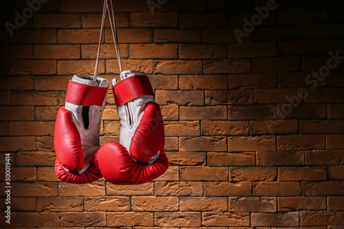 Pair of boxing gloves hanging against brick wall © Pixel-Shot