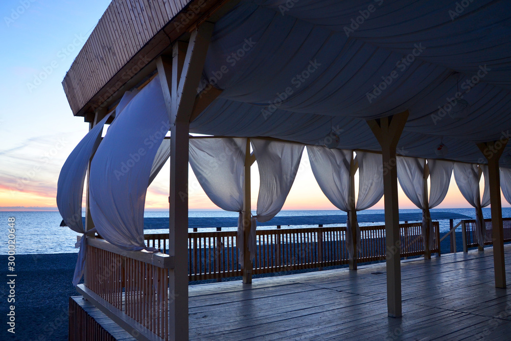  gazebo with curtains by the sea at sunset