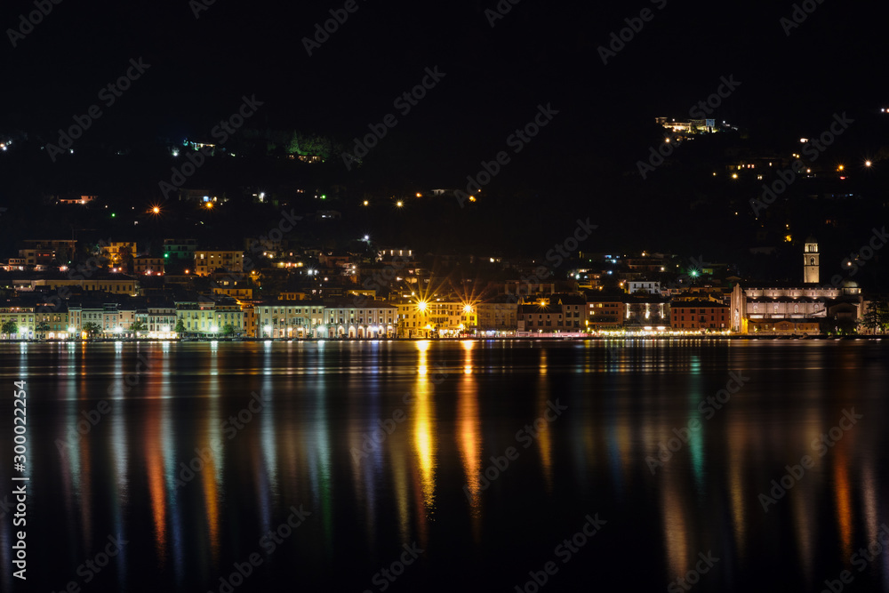 Evening panoramic view of the center of Salo Lake Garda. City night lights reflected in water