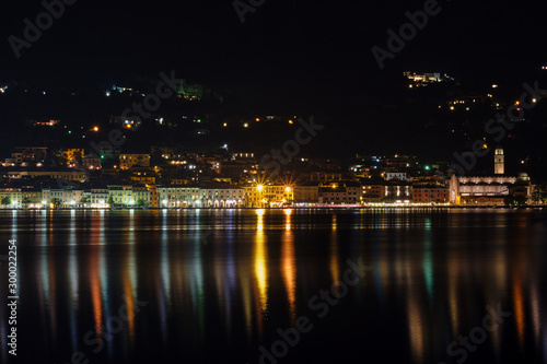 Evening panoramic view of the center of Salo Lake Garda. City night lights reflected in water