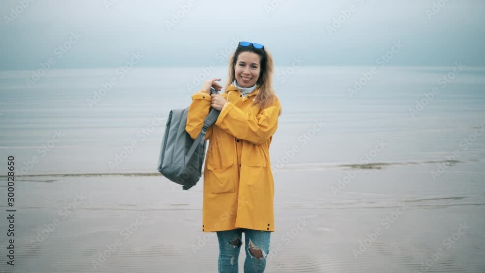 A tourist woman is putting on a backpack and smiling A tourist woman is putting on a backpack and smiling