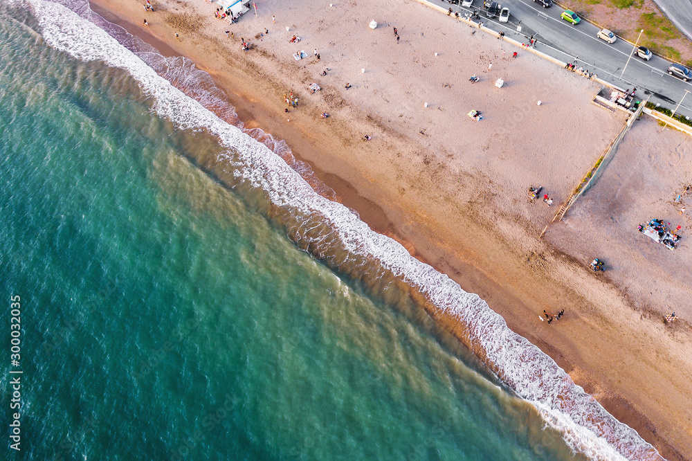 Aerial top down view of Italian resort beach with sand and foaming sea waves at sunset. Ostia Lido near Rome, Italy.
