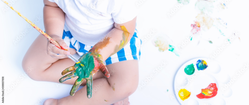 Happy asian baby child use paintbrush draw water color or fingerpaint on hand Happy asian baby child use paintbrush draw water color or fingerpaint on hand