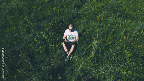 Top view aerial photo of man sitting on the grass with laptop