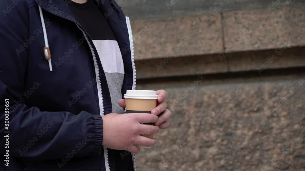 Young man drinking coffee from cup in the morning at street in a city. Breakfast Young man drinking coffee from cup in the morning at street in a city. Breakfast