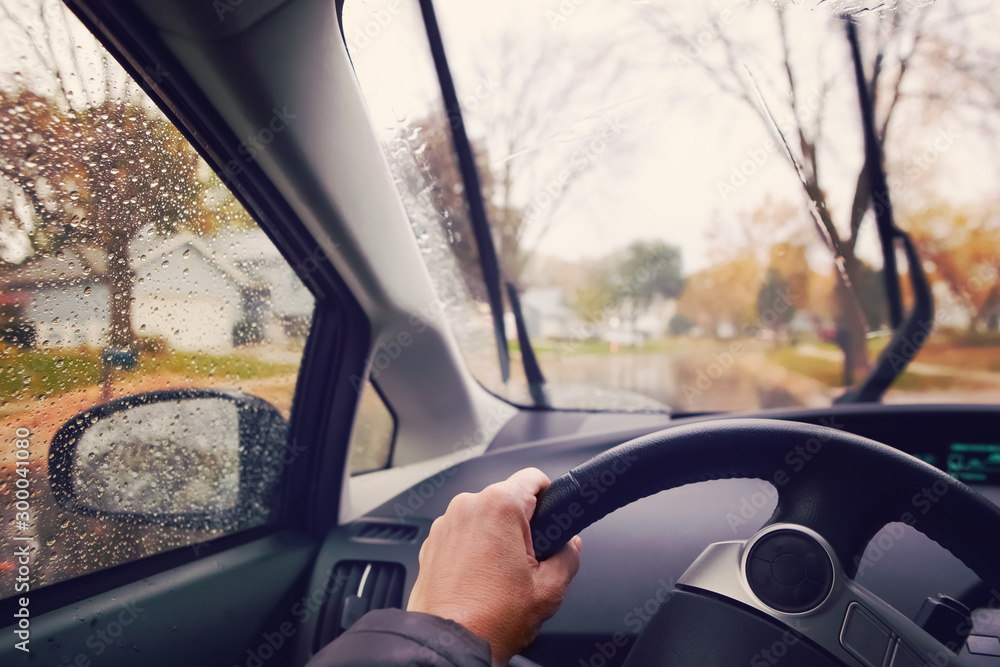 Hand on steering wheel on a rainy autumn afternoon