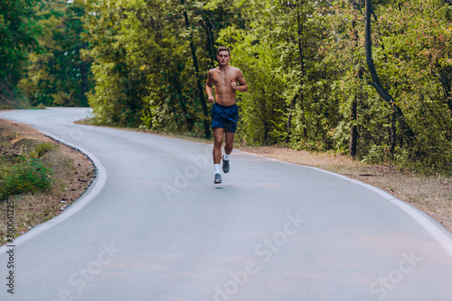 Male runner jogging and running on road in nature landscape