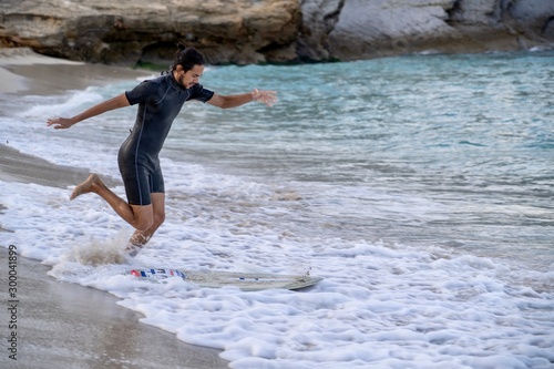 Man dropping on his skimboard in order to slide into a wave and ride it mixing skate and surf in one sport