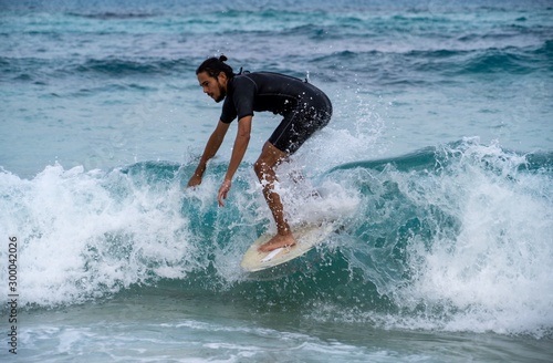 Young man riding a wave on a skimboard (a mix of surf and skate) in Cala Mesquida (Mallorca, Spain) © Daniel