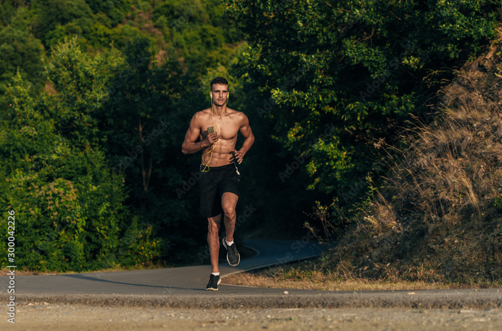 Handsome jogger working out for marathon outside in summer