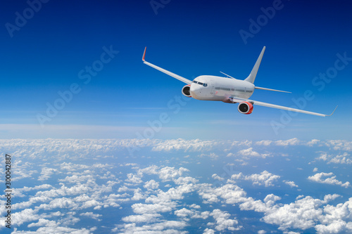 Biały samolot leci ponad chmurą