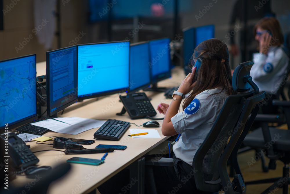 Security guard monitoring modern CCTV cameras in a surveillance room. Group of security guards sitting and monitoring. Security guard monitoring modern CCTV cameras in a surveillance room. Group of security guards sitting and monitoring.