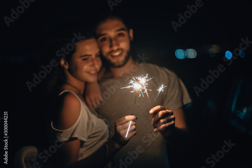 Caucasian man and woman couple playing with sparklers celebration