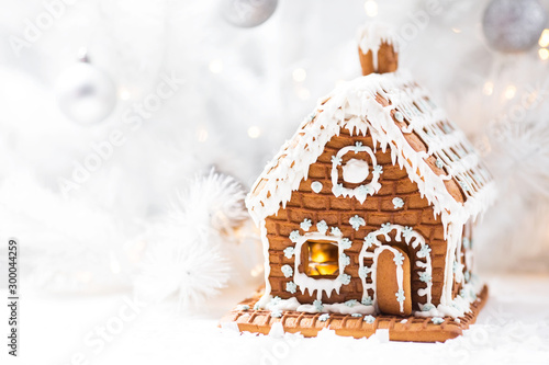 Homemade gingerbread house, white Christmas tree and garland light.