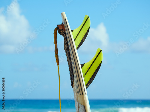 Surfboard with fins and leash on a beach at the ocean
