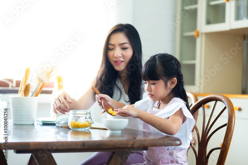 Mother and child daughter Spread butter on bread in the morning. happy family in the kitchen