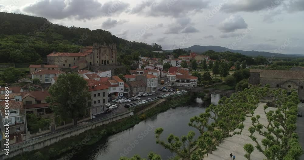 Aerial: Drone approaching bridge over Sar River amidst Convento del carmen and Iglesia de Santiago de Padron in town against cloudy sky Aerial: Drone approaching bridge over Sar River amidst Convento del carmen and Iglesia de Santiago de Padron in town against cloudy sky