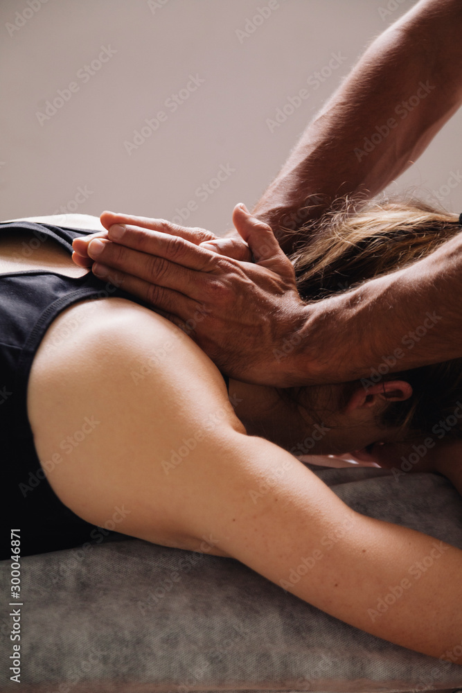 Massage session. Male hands on the neck of a woman