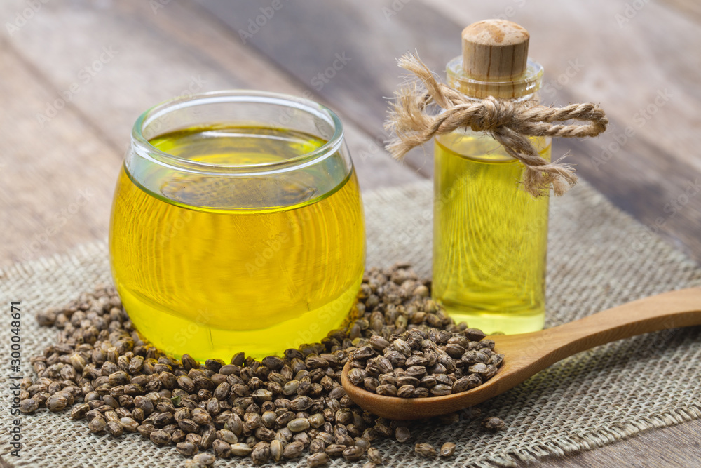 Hemp oil in a glass jar and Hemp seeds on brown wooden table. CBD hemp oil. Hemp oil in a glass jar and Hemp seeds on brown wooden table. CBD hemp oil.