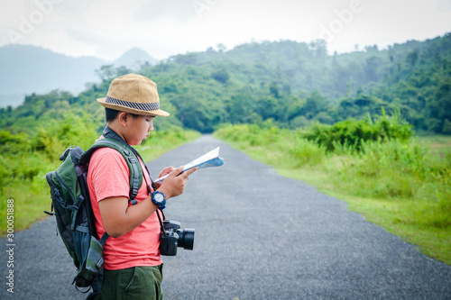 Asian boy traveling nature Carrying a camera carrying a map to study the route