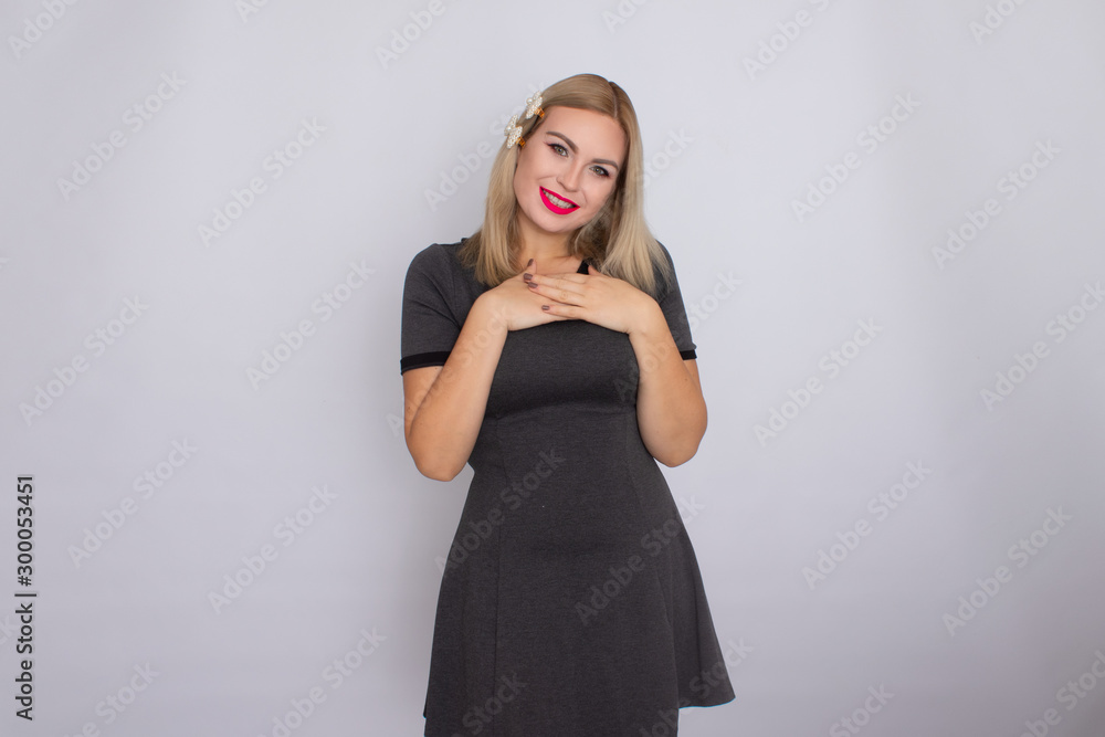 Attractive blonde beauty in grey dress posing on white background Attractive blonde beauty in grey dress posing on white background