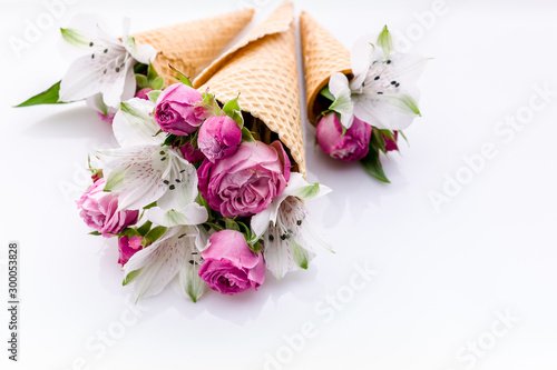 Wedding decoration. Small bouquets of flowers in waffle cones on a white background. Rose and alstrameria. Theme for greeting cards or wedding invitations. Copy space