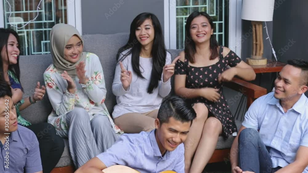 Young happy friends having party, one playing guitar and the other singing together Young happy friends having party, one playing guitar and the other singing together