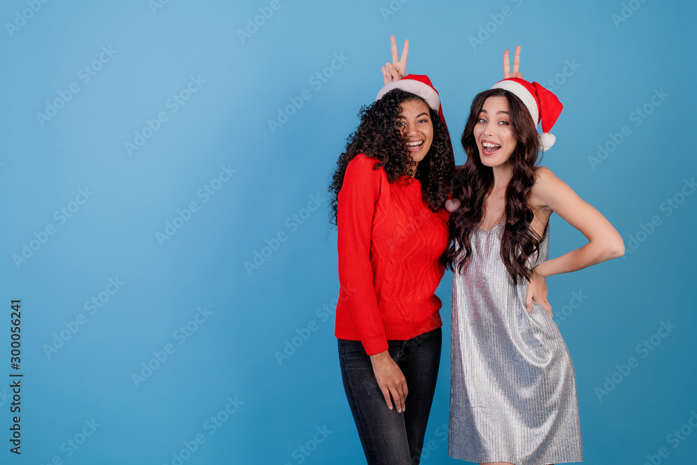 funny women wearing santa hats and festive clothes isolated over blue funny women wearing santa hats and festive clothes isolated over blue