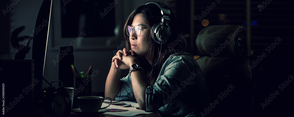 Banner, web page or cover template of Asian Businesswoman sitting and working hard on the table with front of computer desktop in office or workplace with over time, Work hard and too late concept