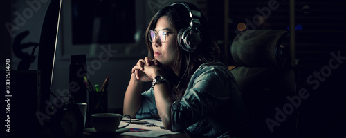 Obraz na płótnie Banner, web page or cover template of Asian Businesswoman sitting and working hard on the table with front of computer desktop in office or workplace with over time, Work hard and too late concept w salonie