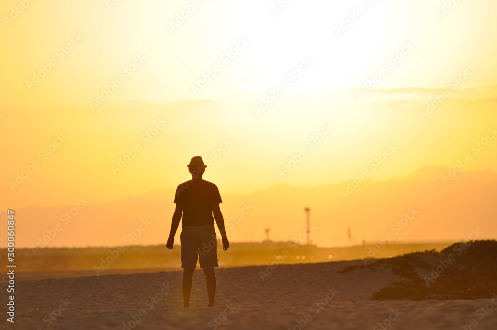 Man on the beach meditating at sunset.