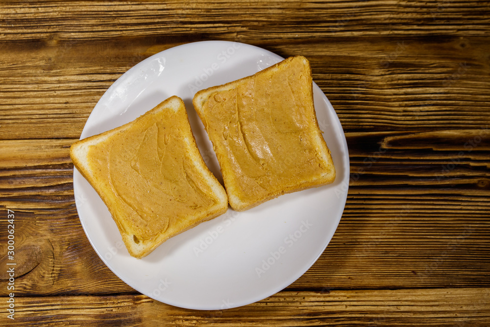 Two slices of bread with peanut butter on wooden table. Top view Two slices of bread with peanut butter on wooden table. Top view