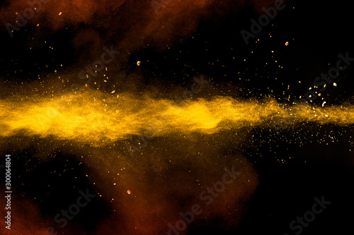 Abstract yellow orange powder explosion on black background.Freeze motion of yellow orange dust particles splash.