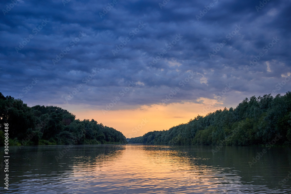 Beautiful bright dramatic sunset over Danube river with forest along riverside Beautiful bright dramatic sunset over Danube river with forest along riverside
