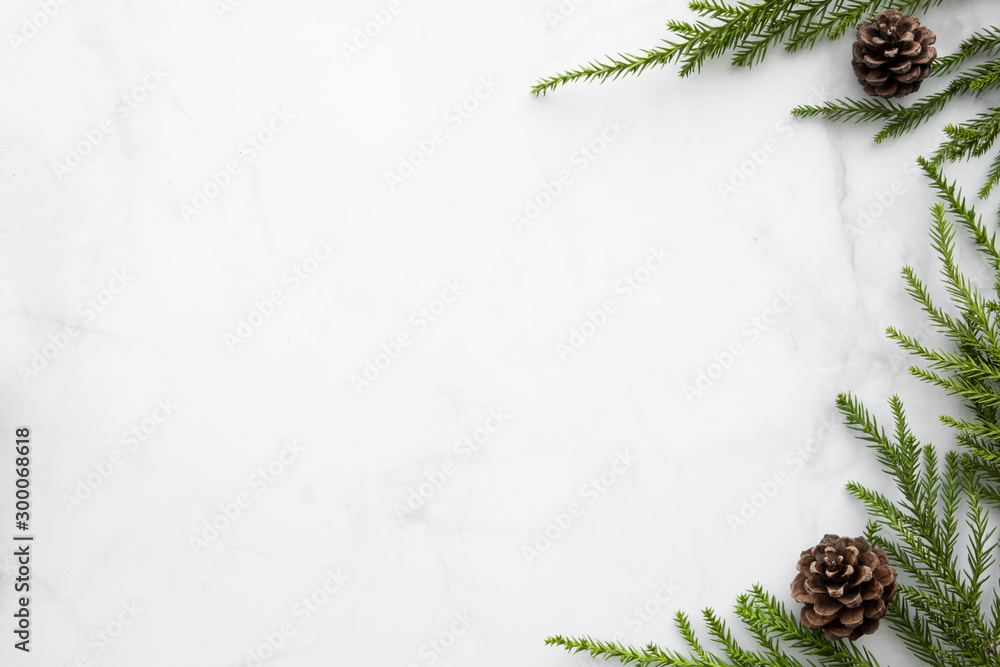 White marble table with Christmas decoration including pine branches and pine cones. Merry Christmas and happy new year concept. Top view with copy space, flat lay. - obrazy, fototapety, plakaty 