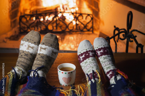 Wallpaper Mural Man and woman in warm knitted socks with cups of hot punch in front of the fireplace Torontodigital.ca