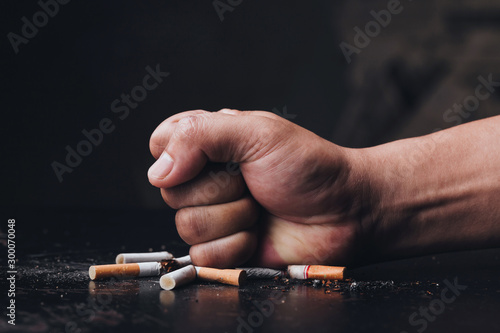 Male hand destroying cigarettes on black background.stop smoking concept. world no tobacco day photo