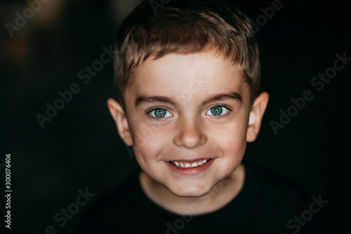 Beautiful portrait of a happy smiling boy with beautiful blue eyes and a beautiful smile. Baby face on black background