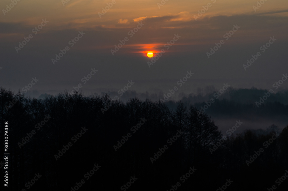Fototapeta premium The sun behind the cloud. Cloudy dawn in the fall.