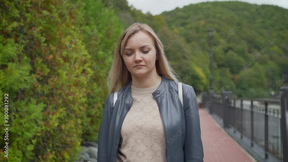 A young girl walks in Sochi on Rosa Khutor. Young tourist walks with a backpack on a city street A young girl walks in Sochi on Rosa Khutor. Young tourist walks with a backpack on a city street