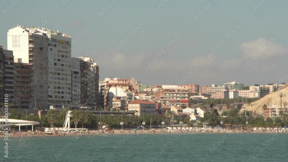People enjoying at beach by buildings in city against sky - Alicante, Spain People enjoying at beach by buildings in city against sky - Alicante, Spain