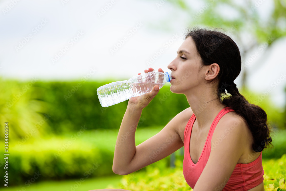 Beautiful woman runner has tired and rest for drinking water after running in the garden. Beautiful woman runner has tired and rest for drinking water after running in the garden.