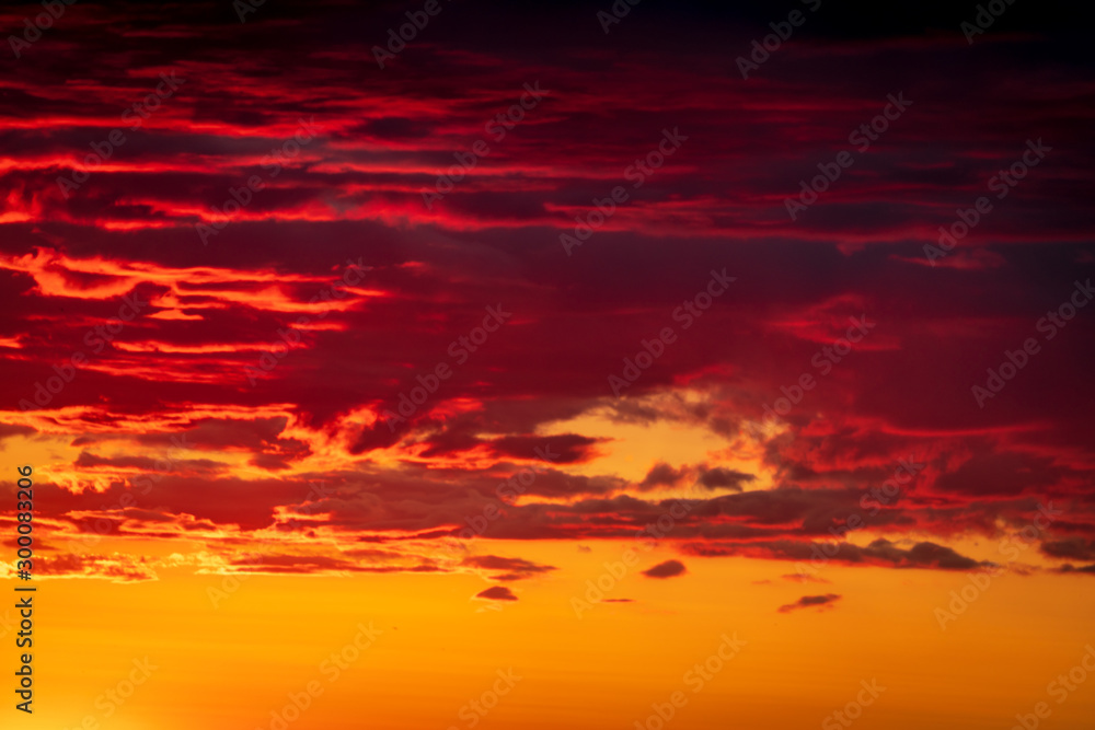 Astonishing sunset sky background with dramatic clouds in deep orange and red tones