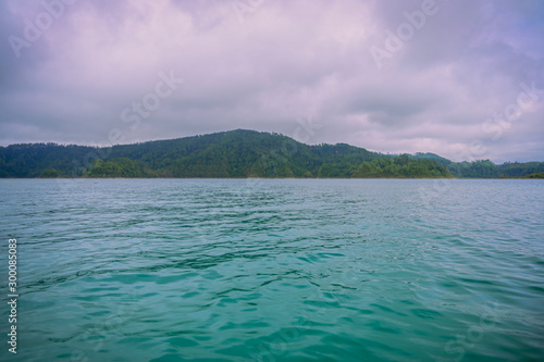 A turquoise lake called Lake of Montebello in Chiapas, Mexico. In the background are mountains woth forest in a cloudy day 