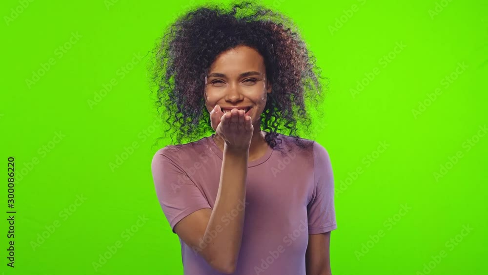 Pleased dark skinned woman has Afro haircut, stretches hands near face, blows air kiss to beloved boyfriend, folds lips, expresses love and affection, over chroma key background. Tender feelings Pleased dark skinned woman has Afro haircut, stretches hands near face, blows air kiss to beloved boyfriend, folds lips, expresses love and affection, over chroma key background. Tender feelings