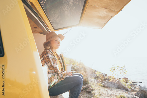Tablou canvas Young blonde Caucasian woman relaxing in her campervan at sunset