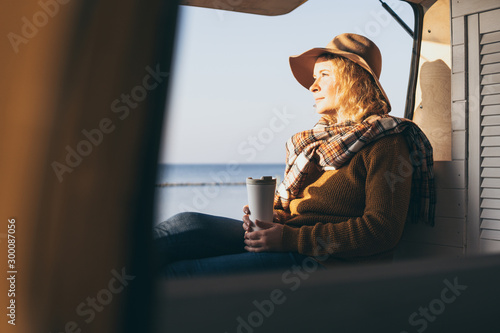 Young blonde Caucasian woman relaxing in her campervan at sunset photo